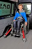 Smiling boy sitting in wheelchair, secured with CLASSIC Line Edition retractors, front view