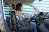 Woman sitting in wheelchair, secured with Dahl Docking System, driving her own car 